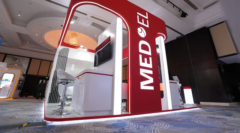 MED-EL exhibition stand with red arch and illuminated logo