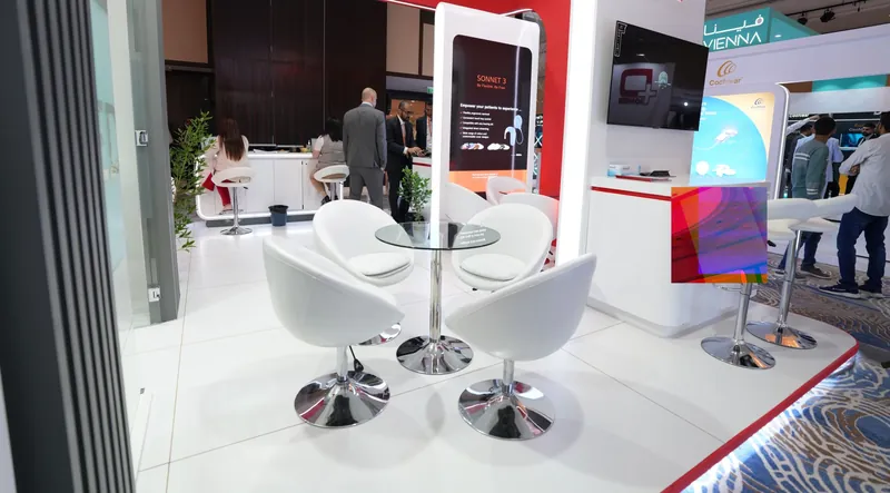MED-EL stand lounge with white chairs and product screens